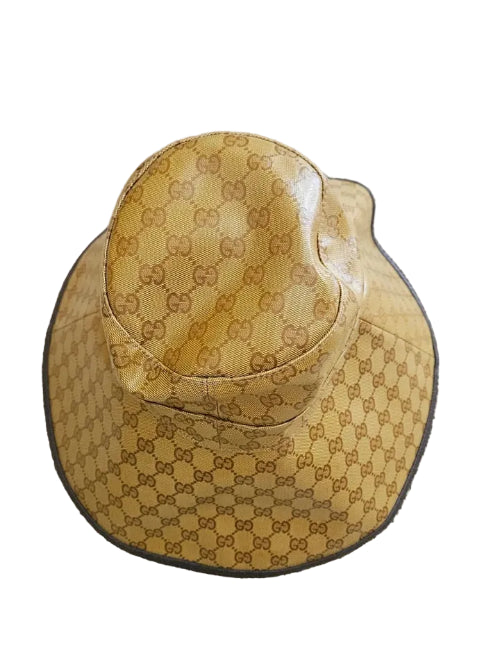 A small woven basket hat in a natural tan color, photographed close-up against a textured gray background.