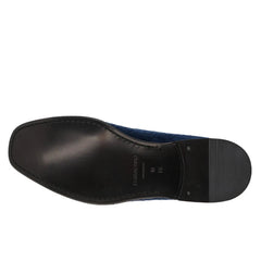 A close-up, top-down view of a shoe's black treaded outsole against a solid white background.