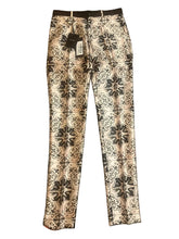 Floral patterned pants with a belt on a plain background