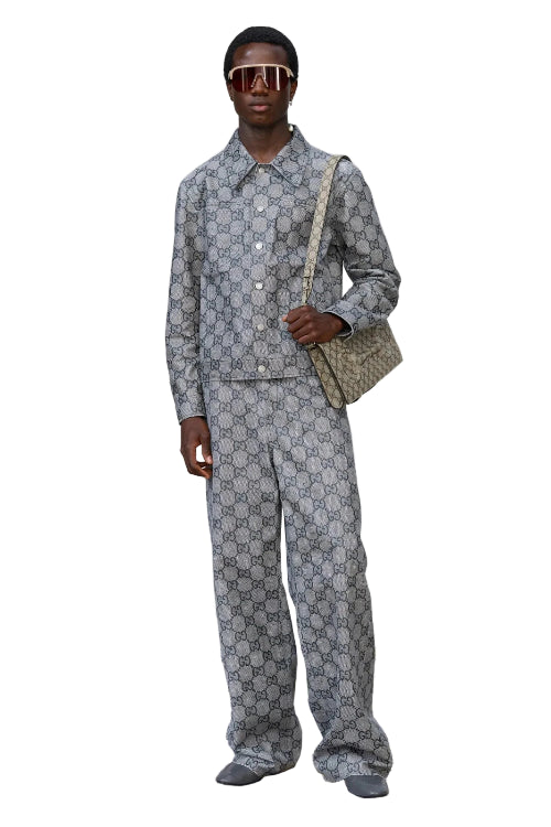 Man wearing a patterned suit with sunglasses and a bag on a white background