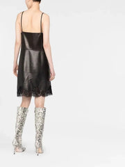 Person wearing a black slip dress with lace details and patterned knee-high boots on a white background