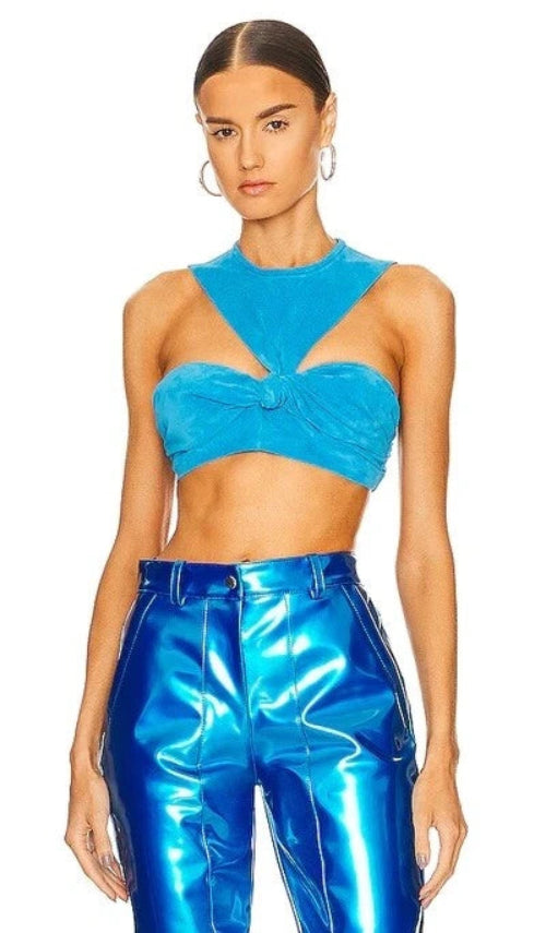 Woman wearing a blue velvet top and high-waisted blue pants on a white background