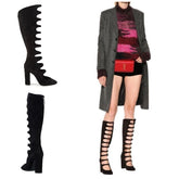 Black knee-high boots with cut-out design worn by a person in a stylish outfit.