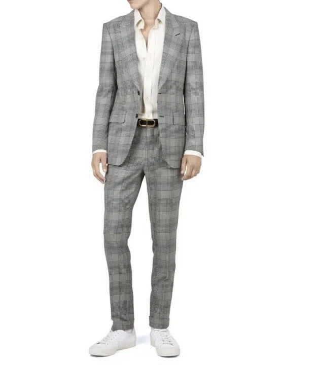 A man wearing a gray and white plaid suit with a white shirt and white sneakers, shown from the neck down against a plain white background.