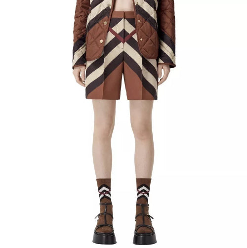 A pair of Burberry Rosalie Kissing Shorts in brown checkered pattern, paired with a brown quilted jacket and brown platform shoes.