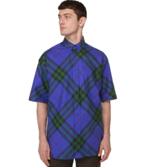 Man wearing a blue and green plaid shirt on a light gray background