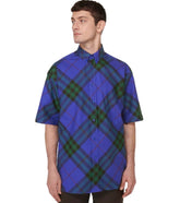 Man wearing a blue and green plaid shirt on a light gray background