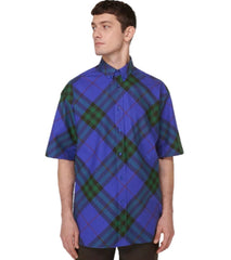 Man wearing a blue and green plaid shirt on a light gray background