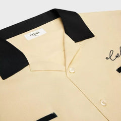 Beige shirt with black collar and Celine label on a light gray background