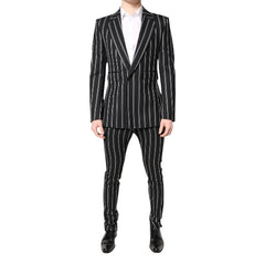 A male model wearing a black striped Dolce & Gabbana two-piece pant suit with a white shirt and black shoes.
