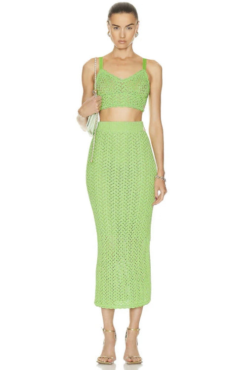 A woman wearing a green two-piece skirt set with a top and a midi skirt.