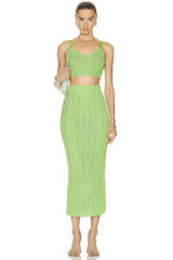 A woman wearing a green two-piece skirt set with a top and a midi skirt.