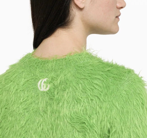 Close-up of a green fluffy garment with a logo on a white background