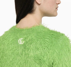 Close-up of a green fluffy garment with a logo on a white background