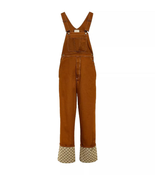 A pair of Gucci brown canvas overalls with adjustable shoulder straps and a cuffed hem, featuring the GG logo in a straight leg style.