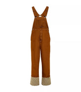 A pair of Gucci brown canvas overalls with adjustable shoulder straps and a cuffed hem, featuring the GG logo in a straight leg style.