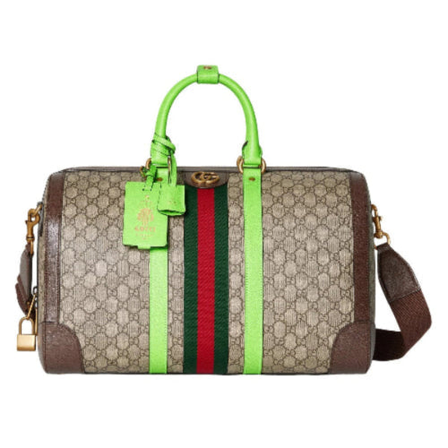 Designer duffle bag with green handle and strap on a white background