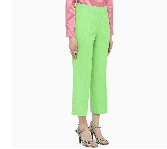 Person wearing bright green pants with a pink top on a white background