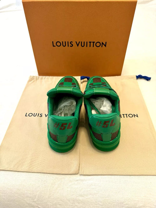 Green children's shoes with red accents on a Louis Vuitton dust bag and box.