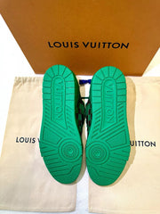Green sole of a Louis Vuitton shoe on a beige pouch with a brown box in the background.