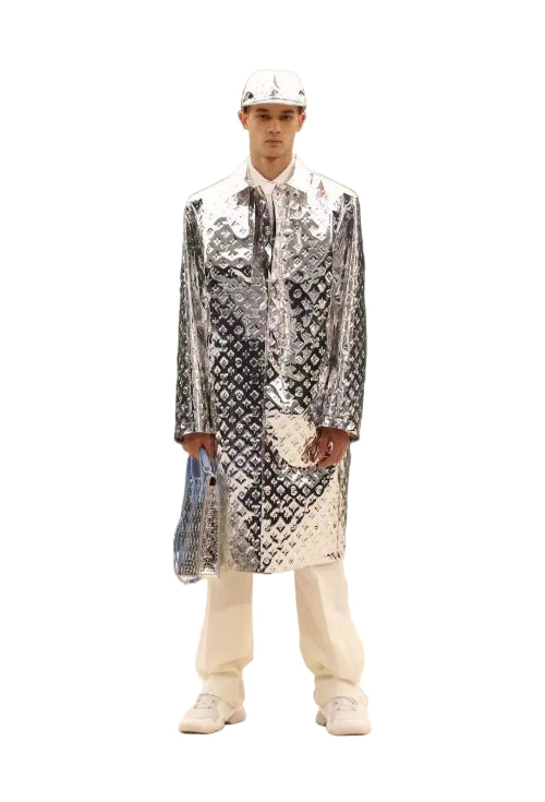 Person wearing a reflective silver jacket with a pattern against a marble wall.