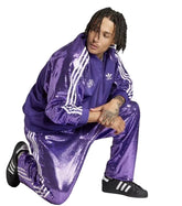 Person wearing a purple Adidas tracksuit on a white background