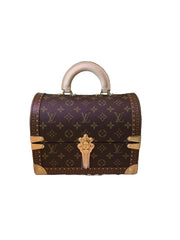 Louis Vuitton monogram handbag on a pink surface with a blurred background of shelves.