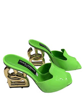 Green high-heeled shoes with gold accents on a metallic surface