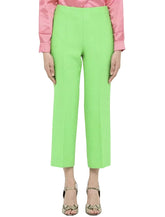 A pair of bright green Gucci ankle pants with a straight leg fit, zipper closure, and worn with a pink top and patterned shoes.