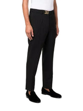 Person wearing black dress pants with a belt on a white background