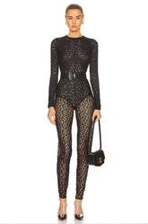 Person wearing a black lace top and leopard print pants with a white background