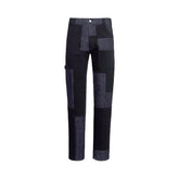 A pair of patchwork patchwork pants in dark denim and black fabric, shown against a plain white background.