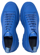 A pair of Alexander McQueen low-top sneakers in a vibrant royal blue color, featuring matching blue laces and chunky soles, shown from a top-down view on a white background.
