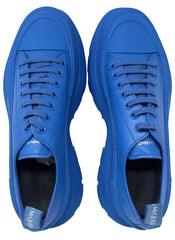 A pair of Alexander McQueen low-top sneakers in a vibrant royal blue color, featuring matching blue laces and chunky soles, shown from a top-down view on a white background.