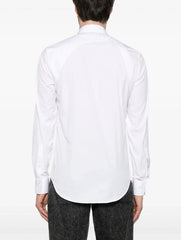 A man wearing a white long-sleeve button-down shirt and black trousers, shown from the back against a plain white background.
