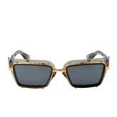 Sunglasses with gold frame and dark lenses on a light gray background