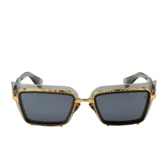 Sunglasses with gold frame and dark lenses on a light gray background