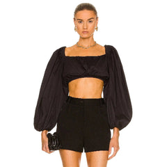 Woman wearing a black outfit with puffed sleeves on a white background