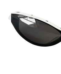 Black sunglasses with dark lenses and a silver metal bridge, shown on a light gray background with a black case partially visible in the upper right.