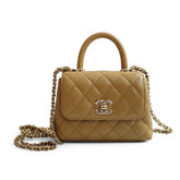 Beige quilted handbag with gold chain and Chanel logo on a white background