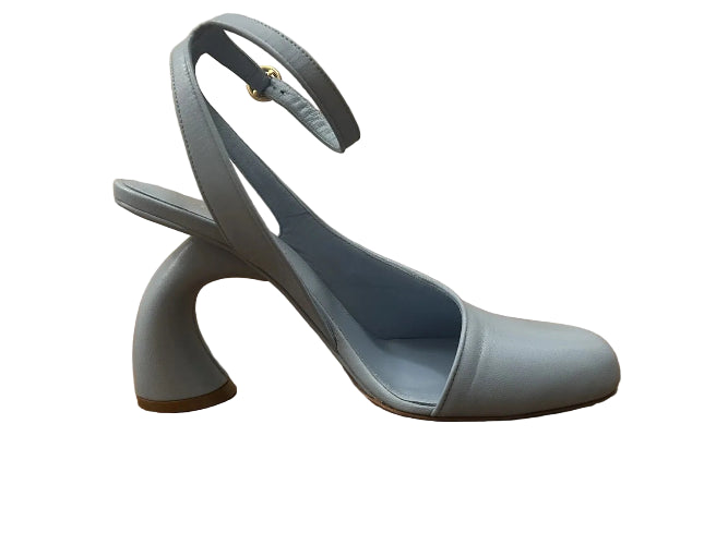 Light blue high-heeled shoe on a wooden floor with a neutral wall background