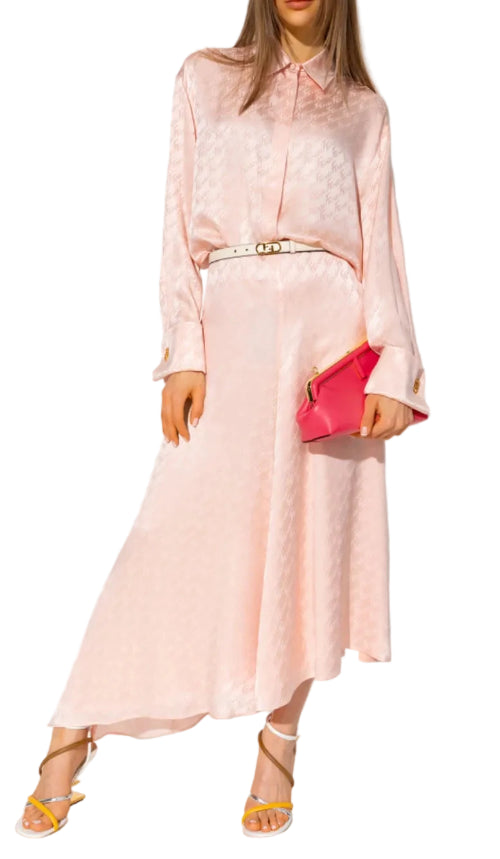 Woman wearing a light pink dress with a red clutch against a white background