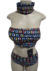 Mannequin wearing a colorful patterned bikini set with a matching neck scarf against a white door background.