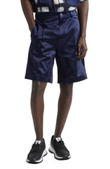 Person wearing navy shorts with a belt and black shoes on a plain background