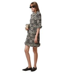 Woman wearing a patterned dress against a white wall