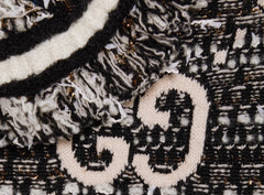 Close-up of a textured fabric with a patterned design, featuring black, white, and gold colors.
