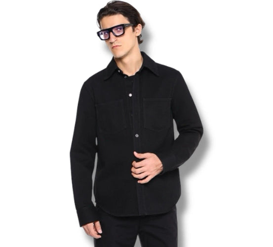 A man wearing a black long-sleeve button-up shirt and black pants, standing against a plain white background.