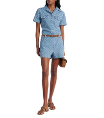 Woman wearing a blue denim romper with a white background