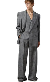 Man wearing a gray checkered suit against a plain background