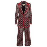 A Gucci two-piece suit featuring a dark red wide-leg blazer and matching trousers with an all-over small geometric print, accented by bright red piping along the lapels, pockets, and cuffs.
